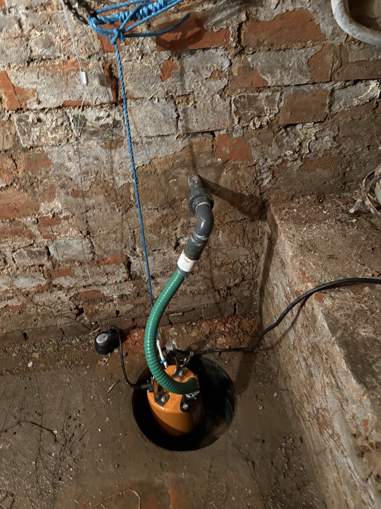 Electrical supply to a cellar sump pump in an old brick basement — switched, protected, and kept clear of the water it's there to shift.