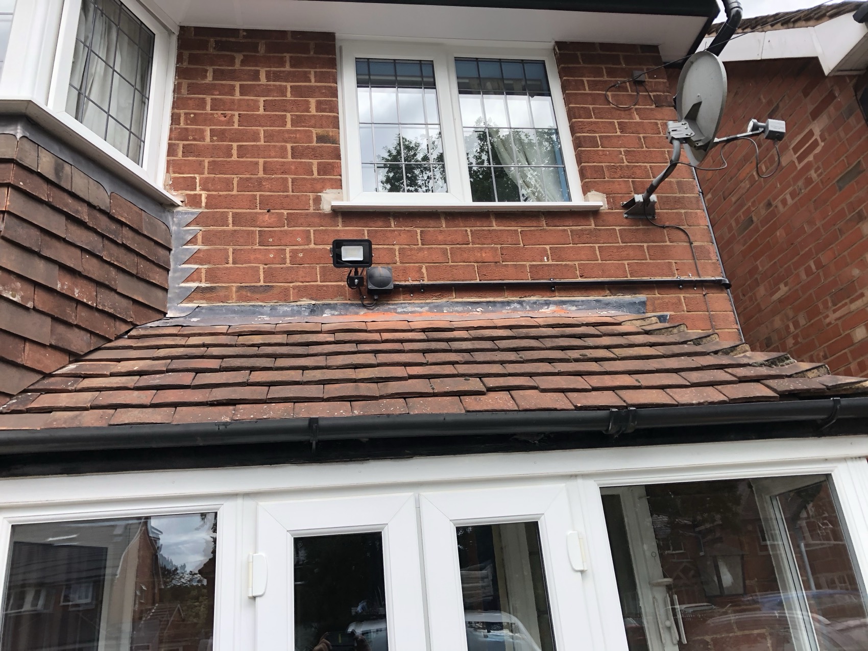 PIR floodlight fitted above a rear extension roof, with the supply clipped in a straight run back under the eaves.